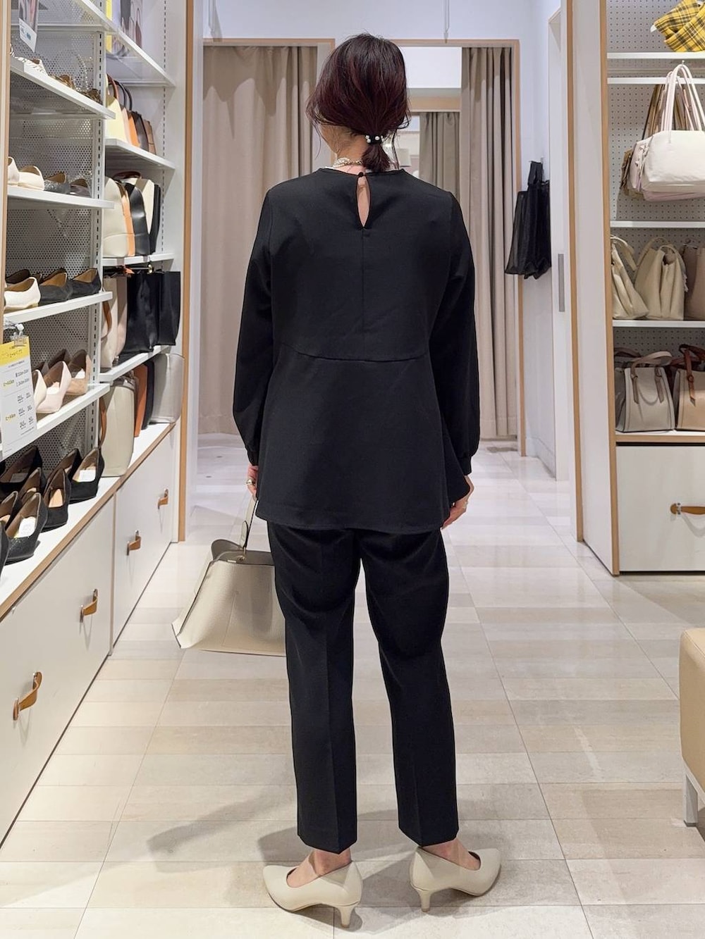 ホワイト系のショルダーバッグ、ブラック系のパンプス、ブラック系のセットアップを着用したレディースの冬コーディネートの7枚目の写真