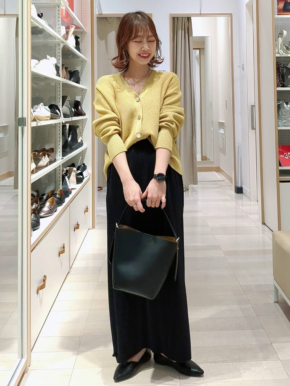 ベージュ系のデニムパンツ、ブラック系のショルダーバッグ、イエロー系のカーディガン/ボレロを着用したレディースの春コーディネートの2枚目の写真