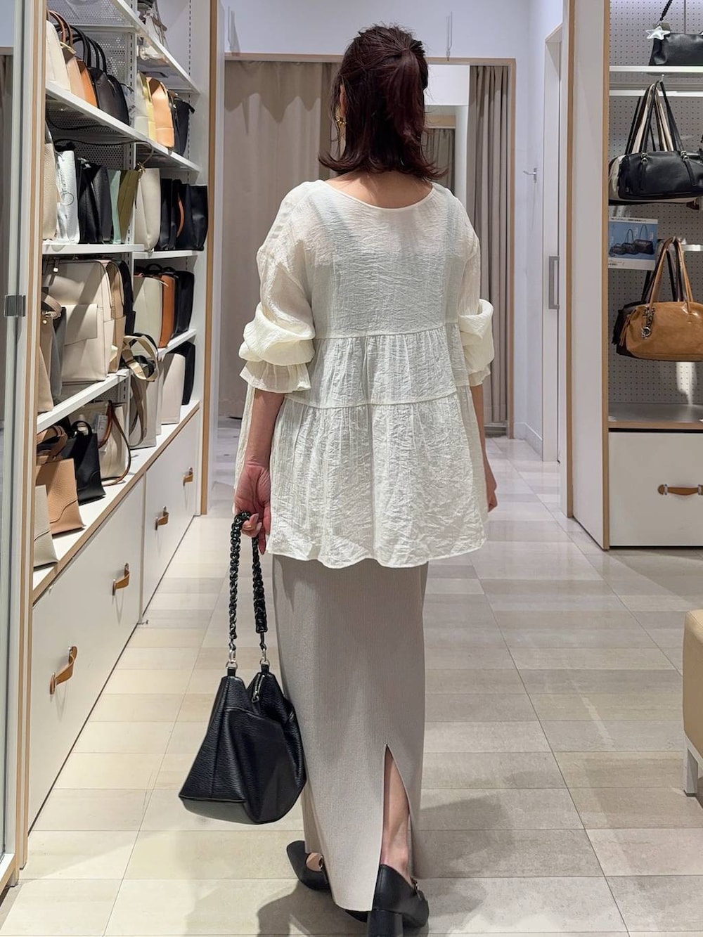 ホワイト系のスカート、ブラック系のパンプス、ゴールド系のネックレスを着用したレディースの春コーディネートの9枚目の写真