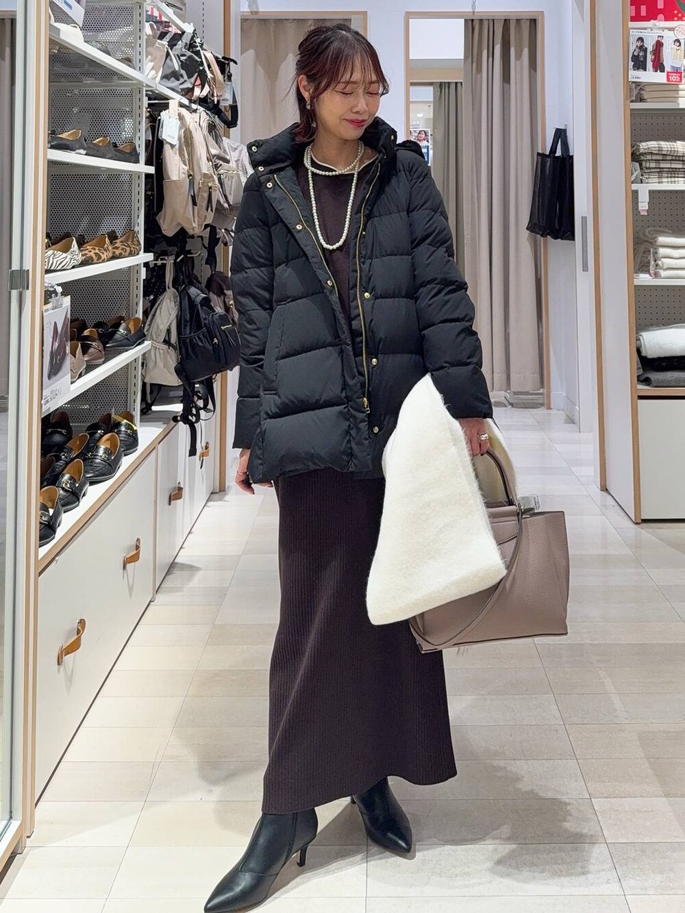 ブラック系のダウンジャケット/コート、ブラウン系のワンピース、ブラック系のブーツを着用したレディースの冬コーディネートの2枚目の写真