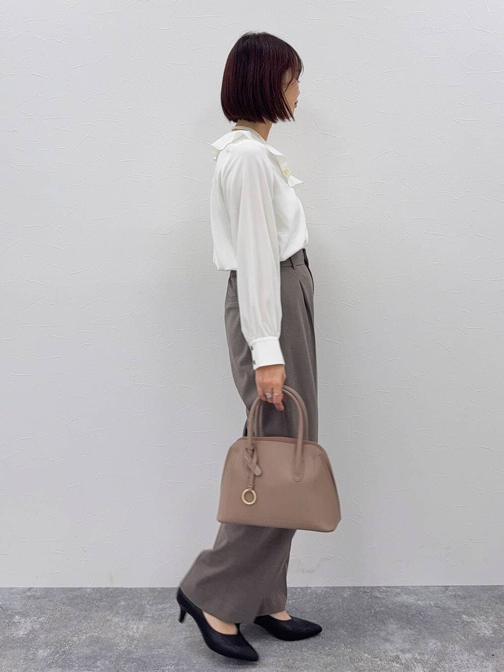 ベージュ系のショルダーバッグ、ブラック系のパンプス、ブラウン系のスラックスを着用したレディースの秋コーディネートの5枚目の写真