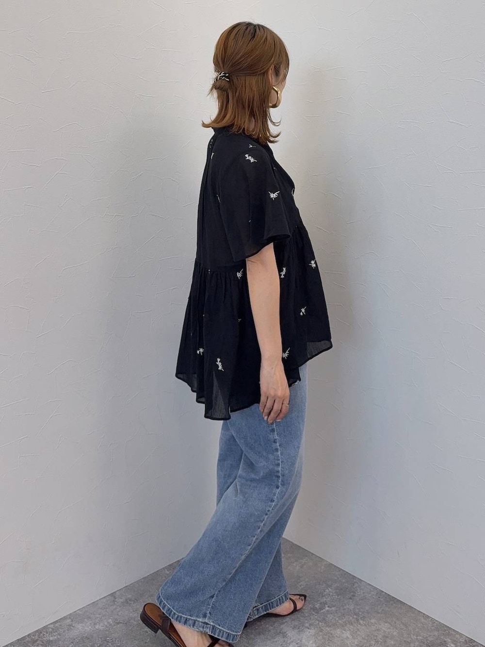 ブルー系のデニムパンツ、ブラウン系のボストンバッグ、ブラウン系のサンダルを着用したレディースの夏コーディネートの5枚目の写真