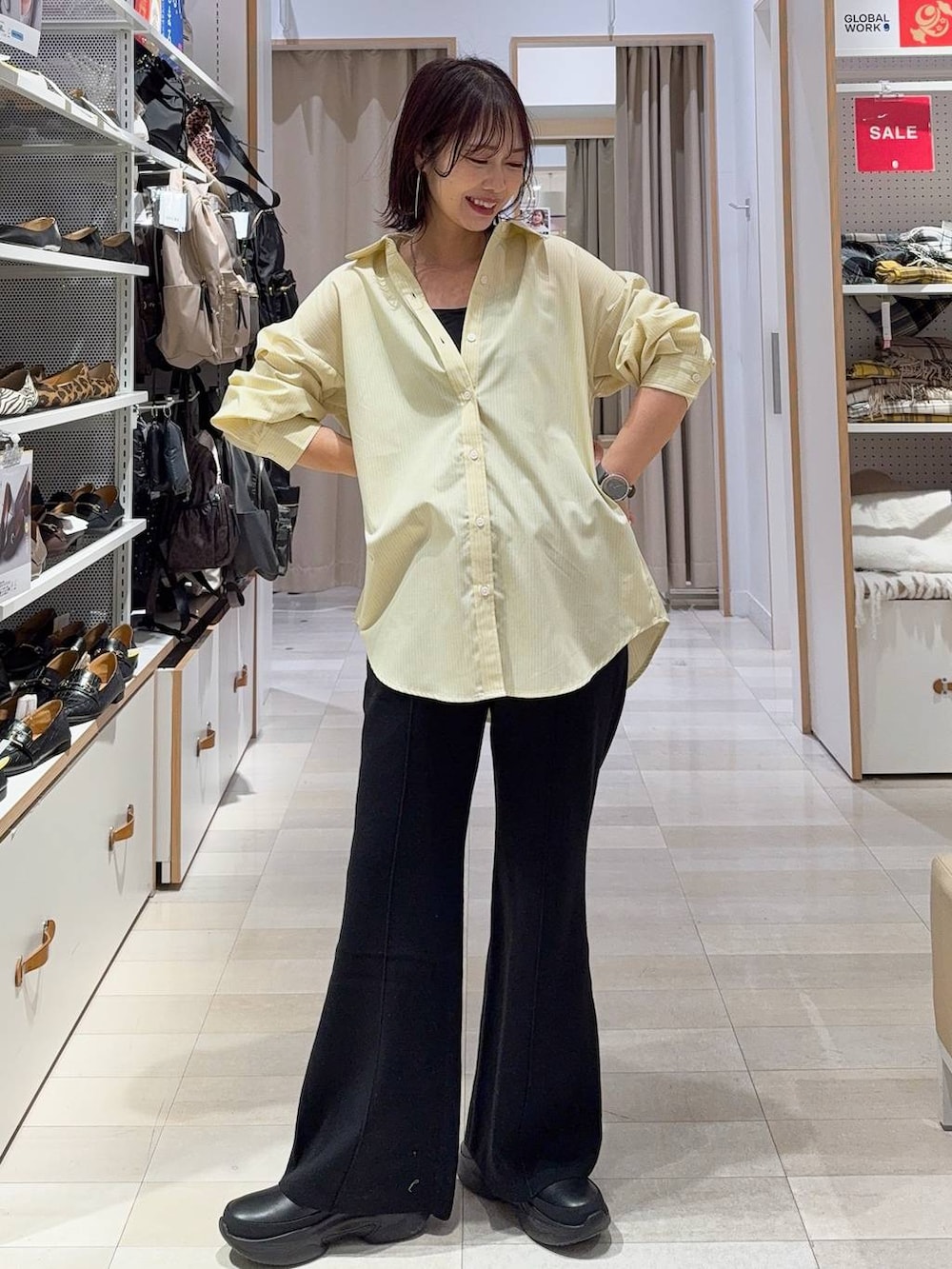 グレー系のニット/セーター、イエロー系のシャツ/ブラウス、ベージュ系のトートバッグを着用したレディースの冬コーディネートの2枚目の写真