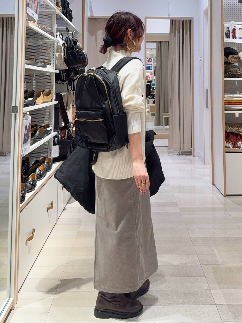 ブラック系のダウンジャケット/コート、ブラウン系のスカート、ホワイト系のニット/セーターを着用したレディースの冬コーディネートの5枚目の写真