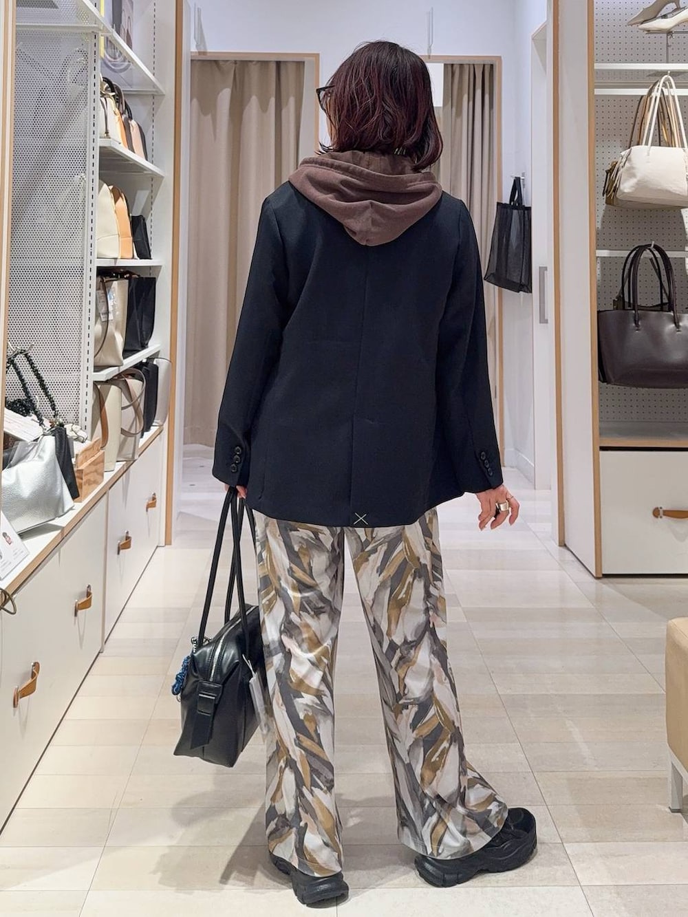 ブラック系のボストンバッグ、ブラック系のスニーカー、ブルー系のテーラードジャケットを着用したレディースの冬コーディネートの7枚目の写真