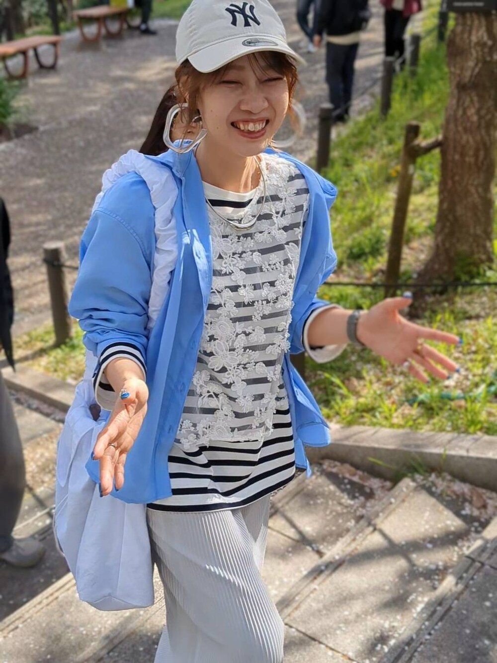 ブルー系のTシャツ/カットソー、グレー系のスカート、ホワイト系のショルダーバッグを着用したレディースの春コーディネートの2枚目の写真