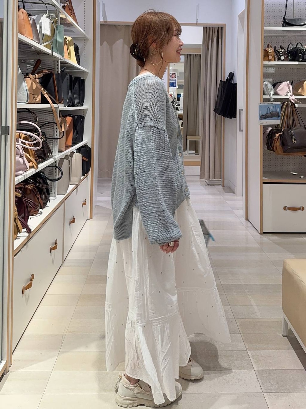 シルバー系のボストンバッグ、ホワイト系のスカート、ホワイト系のタンクトップを着用したレディースの春コーディネートの2枚目の写真