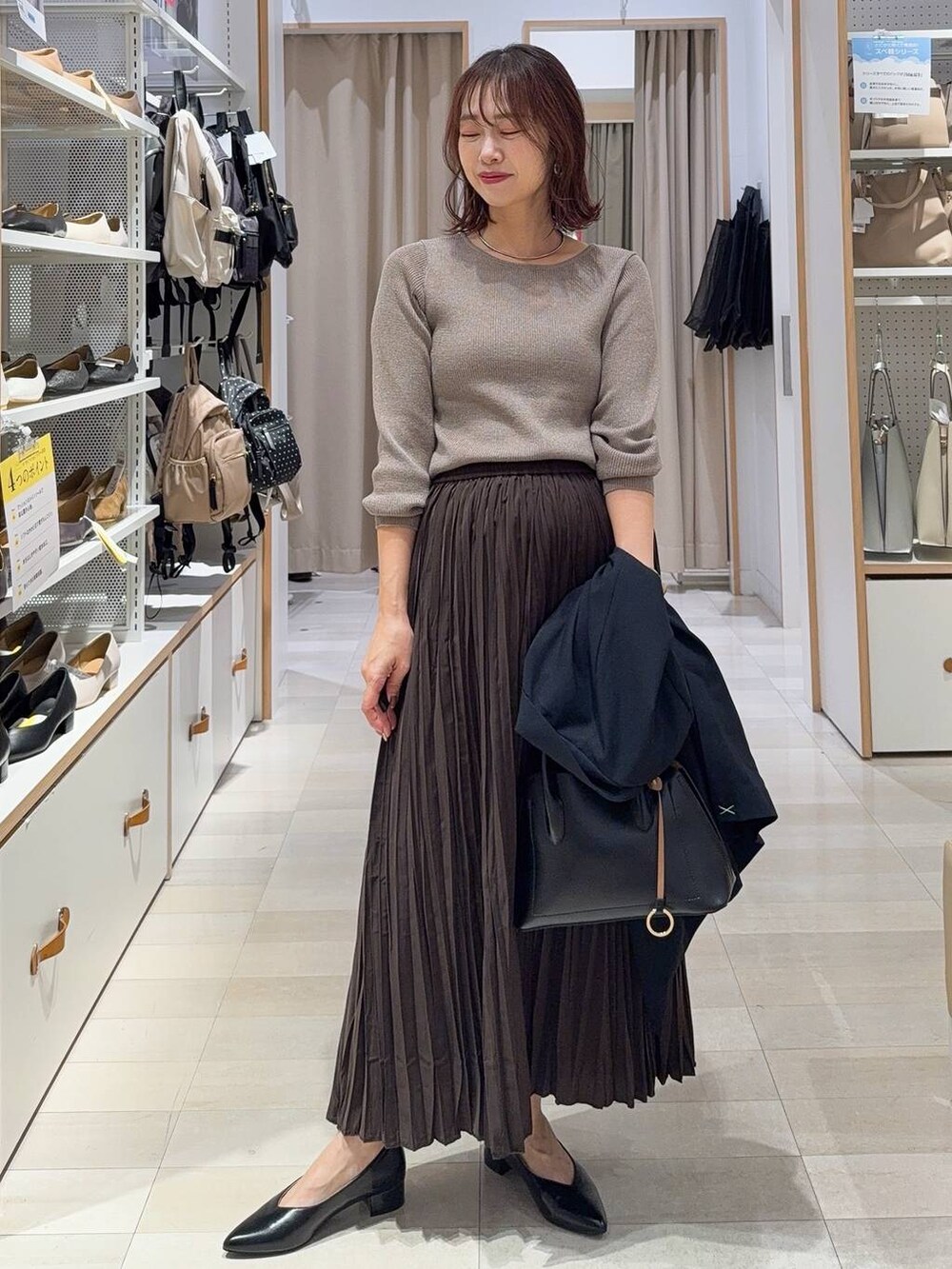 ブラック系のショルダーバッグ、ベージュ系のニット/セーター、ブラウン系のブーツを着用したレディースの秋コーディネートの2枚目の写真