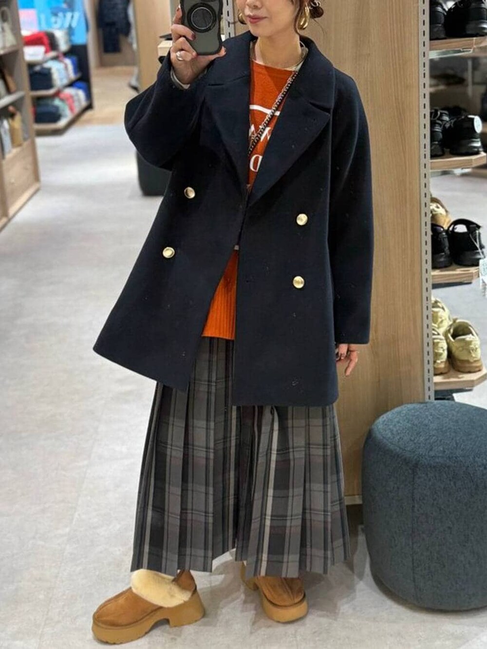 ブラック系のショルダーバッグ、ブルー系のチェスターコート、イエロー系のブーツを着用したレディースの冬コーディネートの2枚目の写真