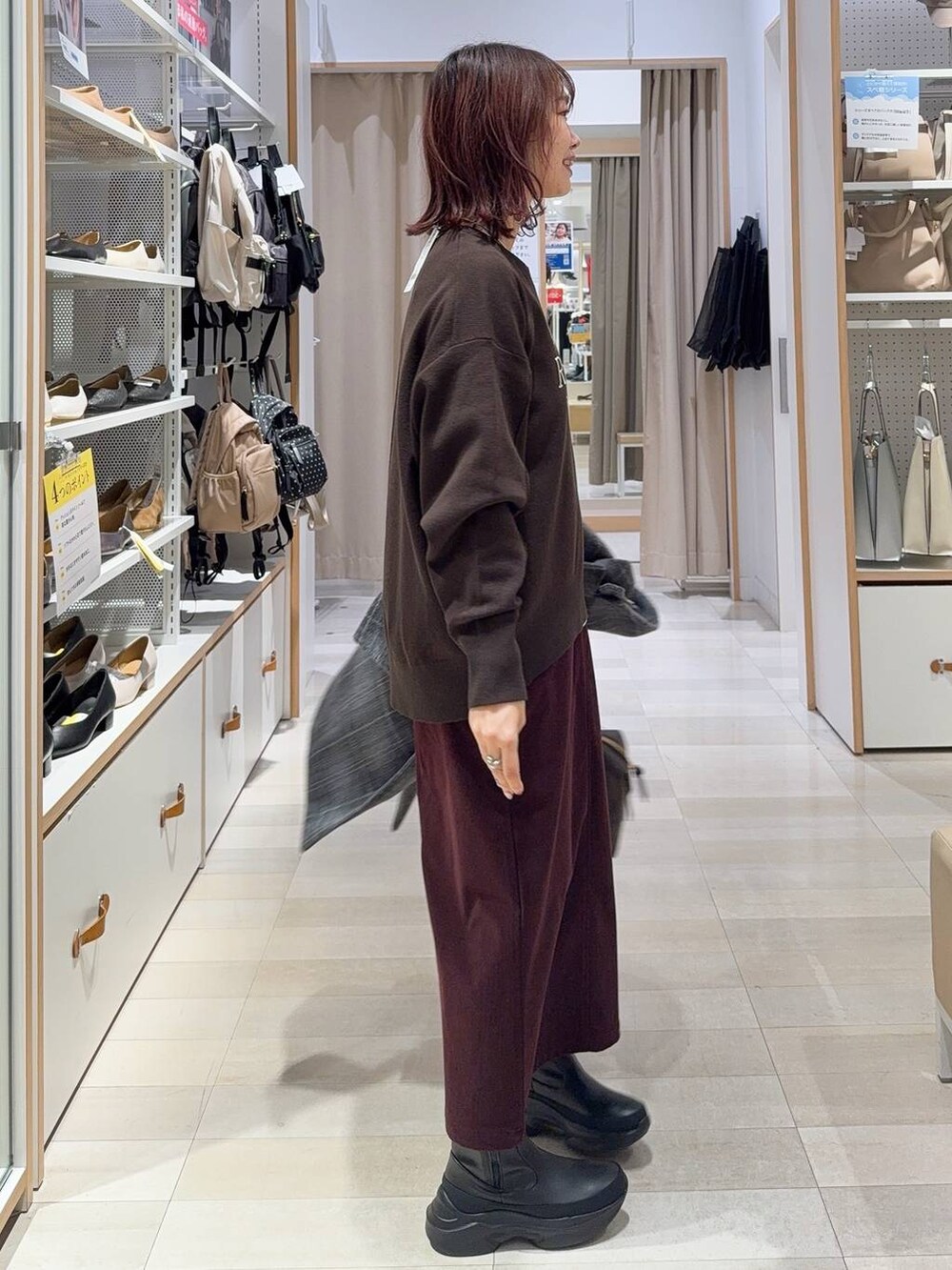 ブラウン系のボストンバッグ、グレー系のチェスターコート、レッド系のスカートを着用したレディースの秋コーディネートの6枚目の写真