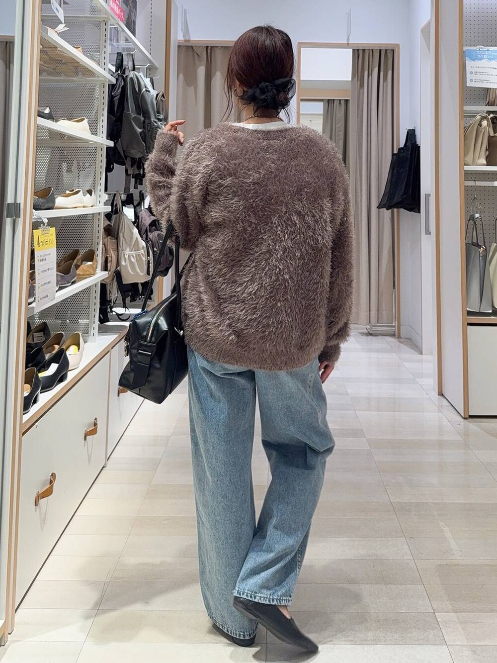 ブラック系のパンプス、ブラック系のボストンバッグ、ブルー系のデニムパンツを着用したレディースの秋コーディネートの5枚目の写真