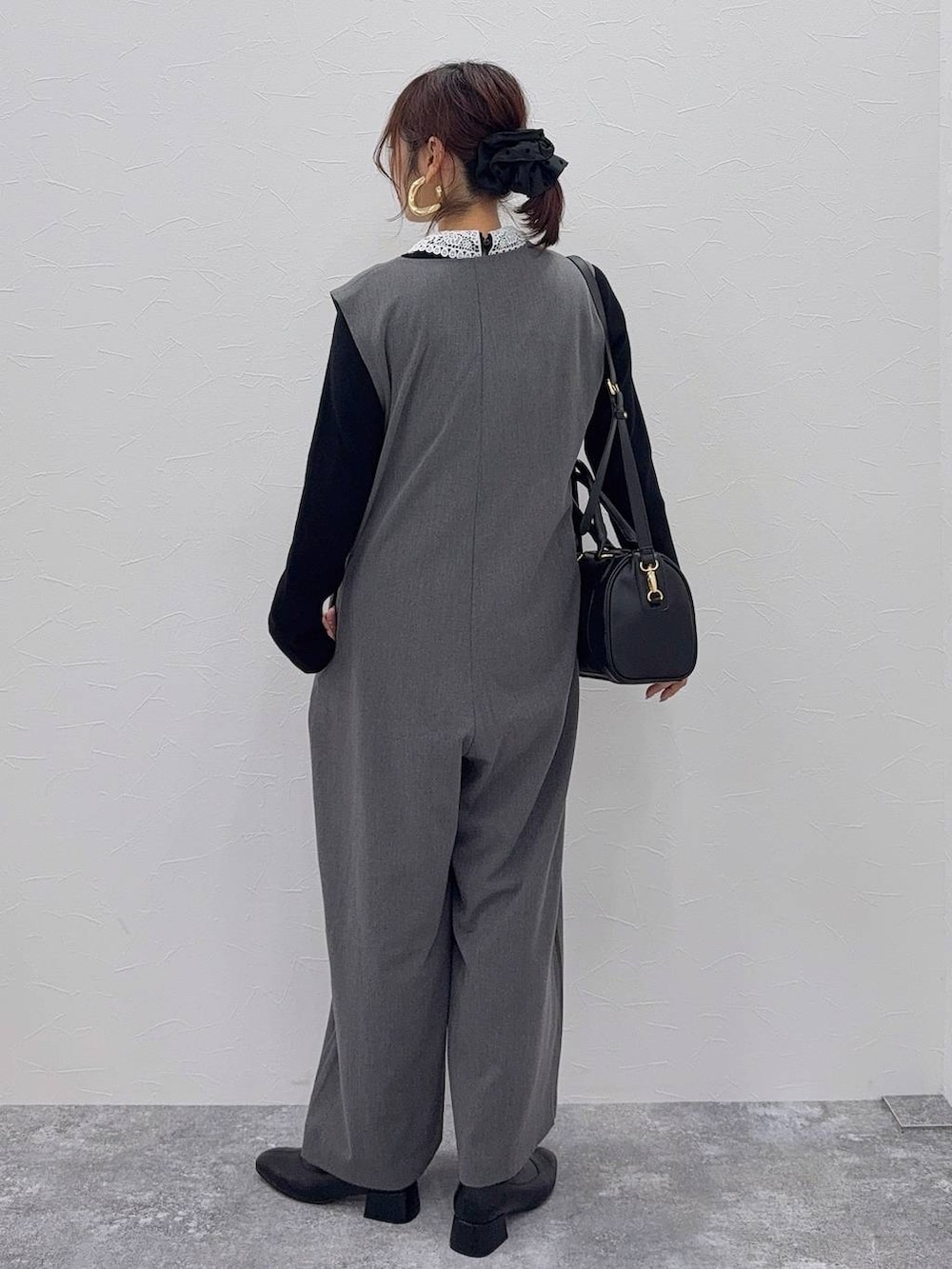 ブラック系のボストンバッグ、ブラック系のブーツ、グレー系のつなぎ/オールインワンを着用したレディースの秋コーディネートの3枚目の写真