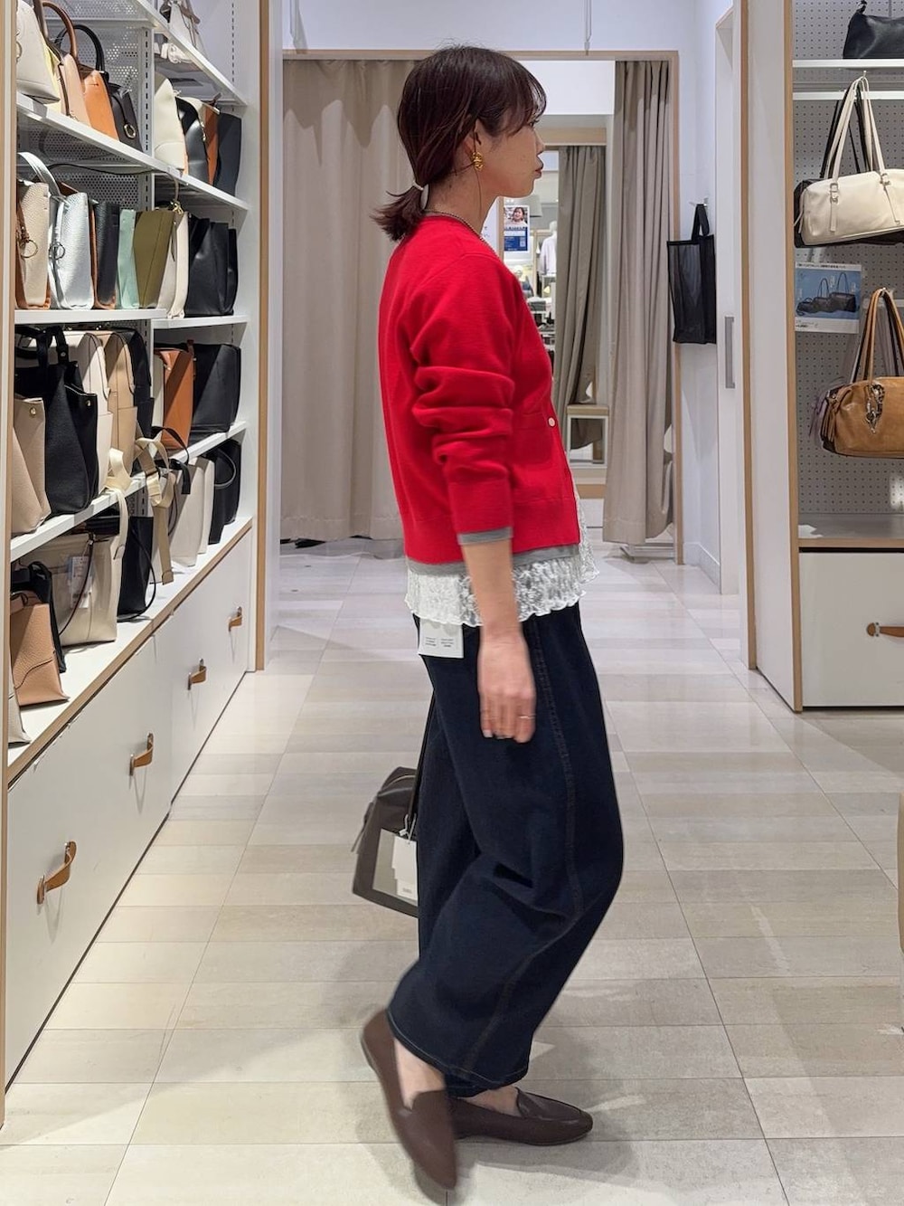 ブラウン系のボストンバッグ、ブルー系のデニムパンツ、レッド系のカーディガン/ボレロを着用したレディースの春コーディネートの8枚目の写真