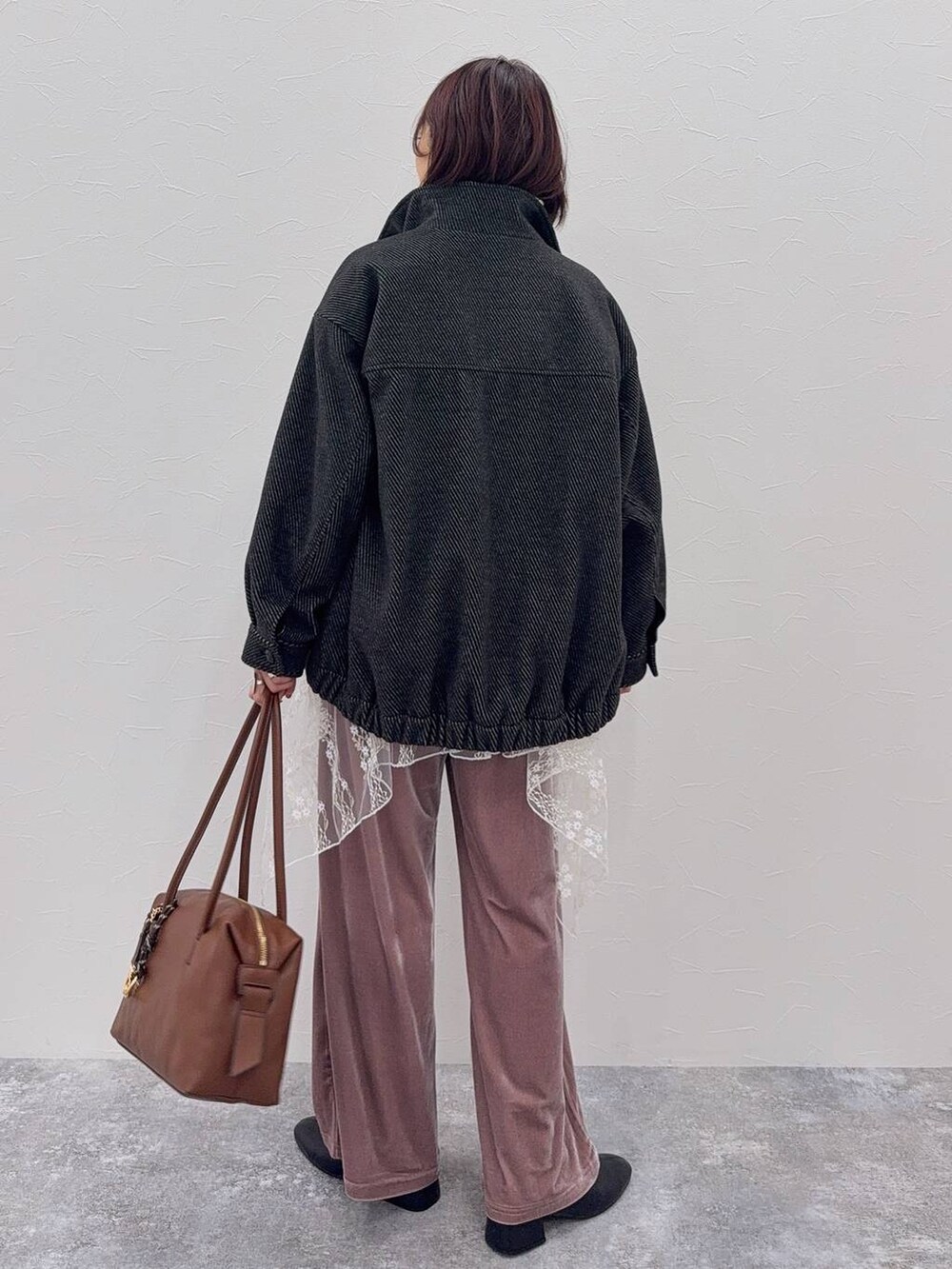 ブラウン系のボストンバッグ、ブラック系のブーツ、ホワイト系のその他トップスを着用したレディースの秋コーディネートの5枚目の写真