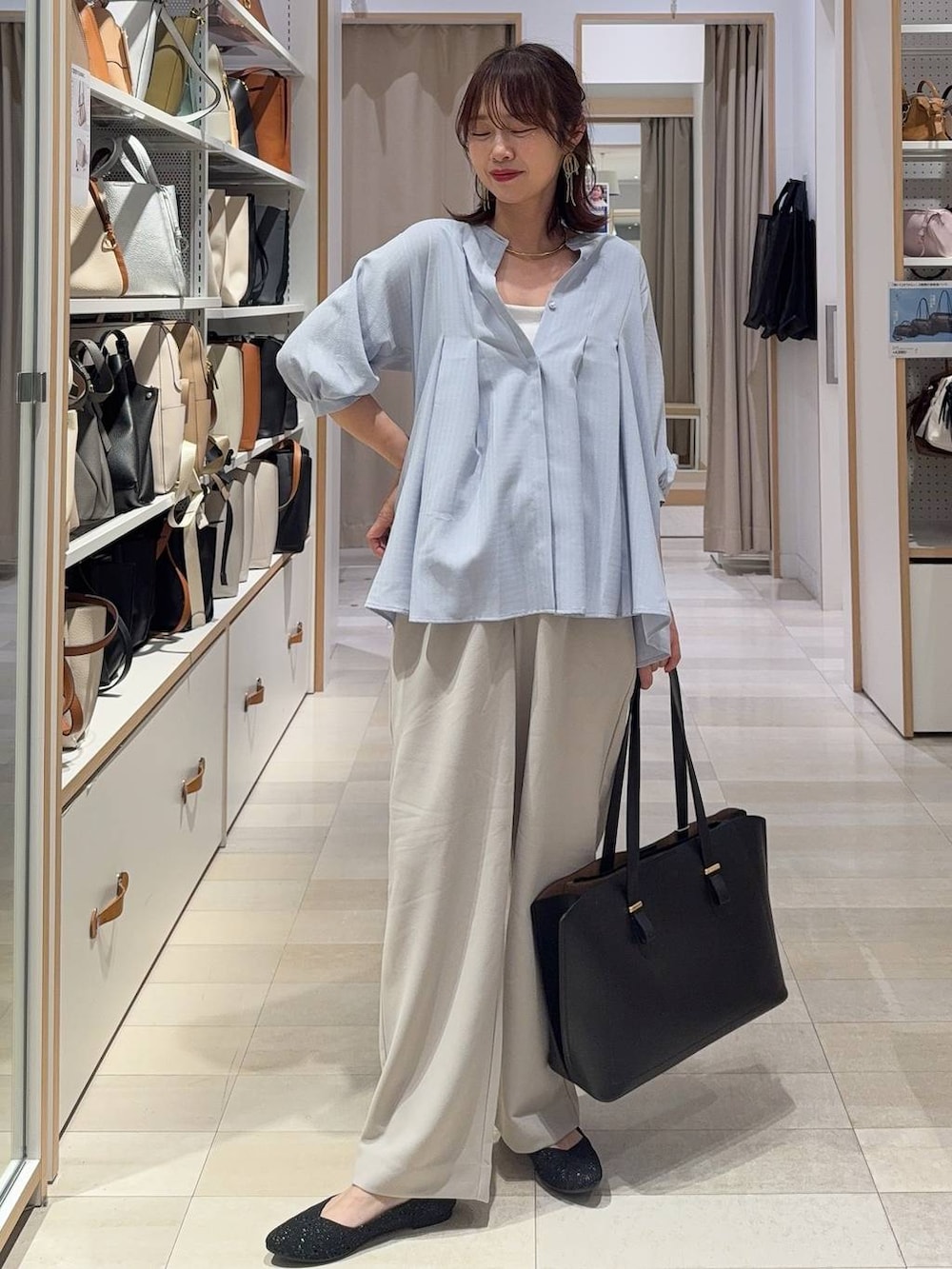 ブラック系のパンプス、ブルー系のスラックス、ホワイト系のカーディガン/ボレロを着用したレディースの春コーディネートの3枚目の写真