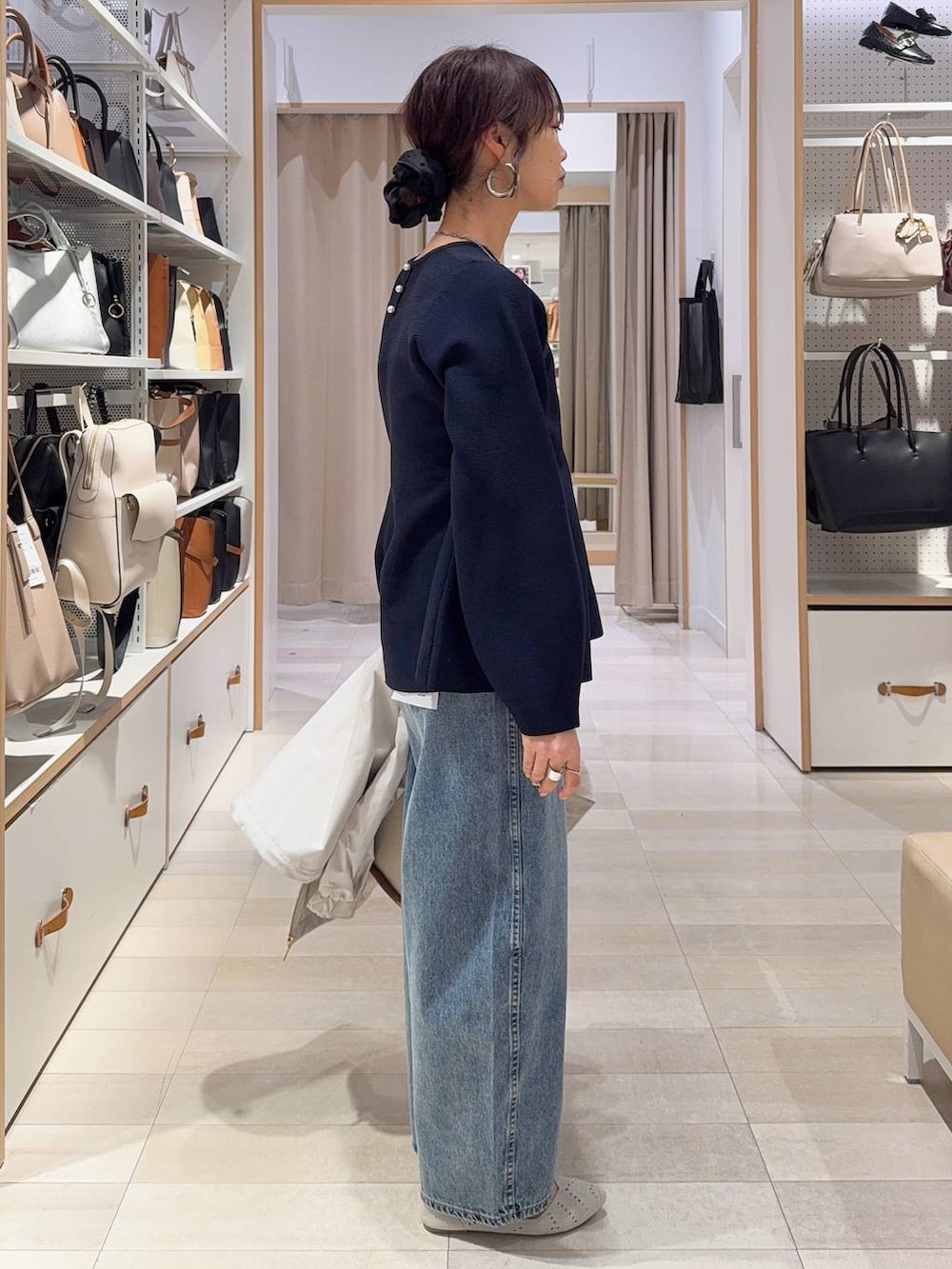 ベージュ系のトートバッグ、ベージュ系のマウンテンパーカー、ブルー系のデニムパンツを着用したレディースの春コーディネートの5枚目の写真