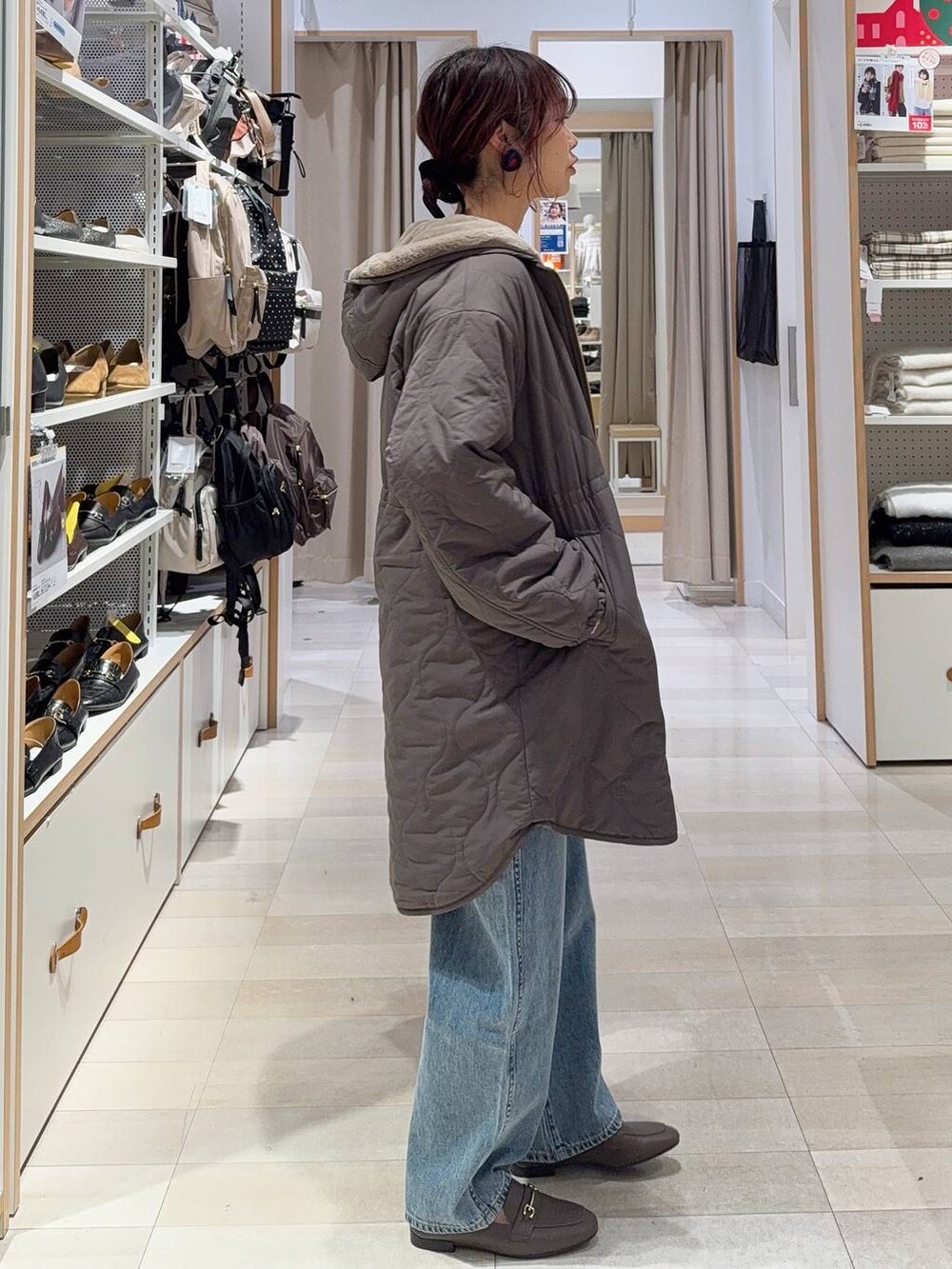 ホワイト系のショルダーバッグ、ブルー系のデニムパンツ、ブラウン系のブルゾンを着用したレディースの冬コーディネートの3枚目の写真