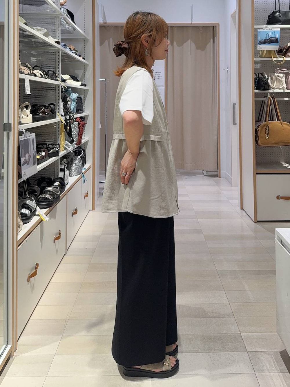 ブラック系のショルダーバッグ、ベージュ系のベスト、ホワイト系のTシャツ/カットソーを着用したレディースの夏コーディネートの5枚目の写真