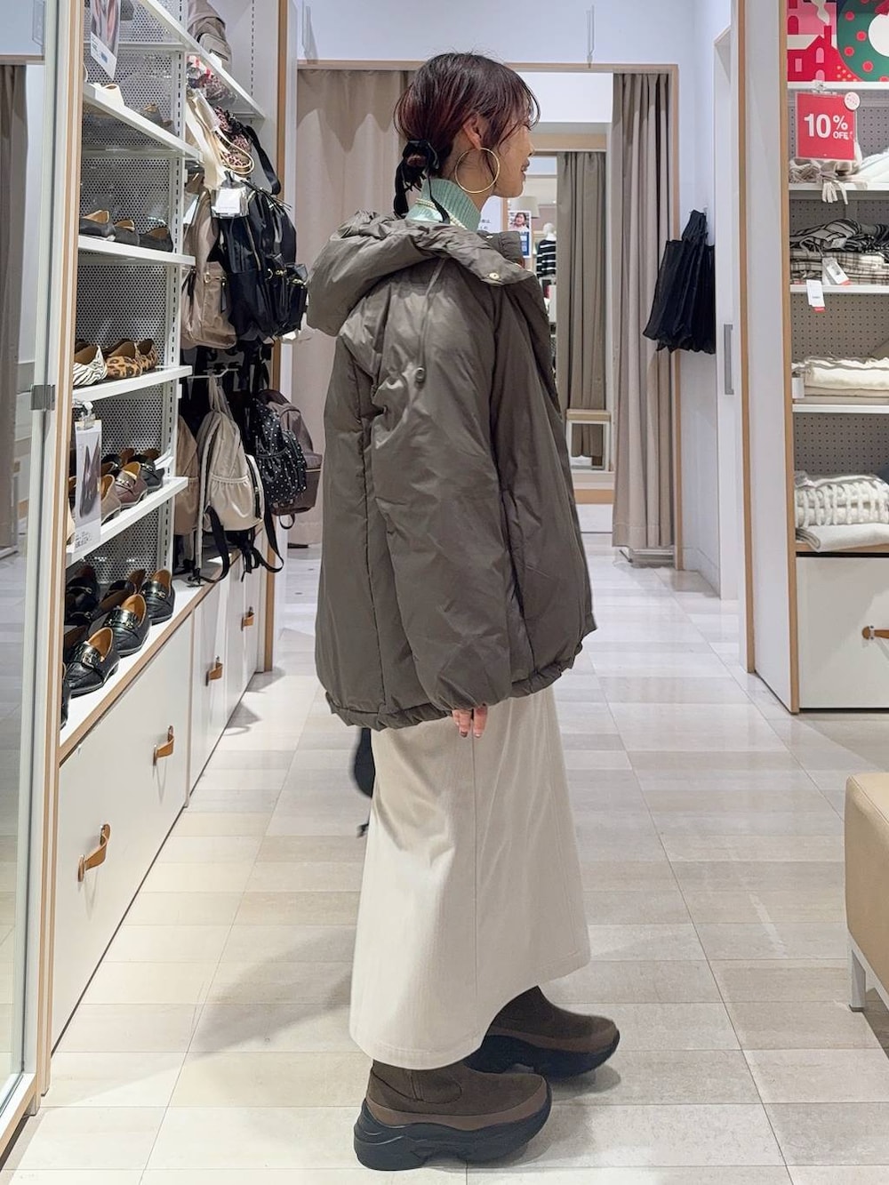 ブラウン系のダウンジャケット/コート、グレー系のスカート、ブラック系のハンドバッグを着用したレディースの冬コーディネートの6枚目の写真