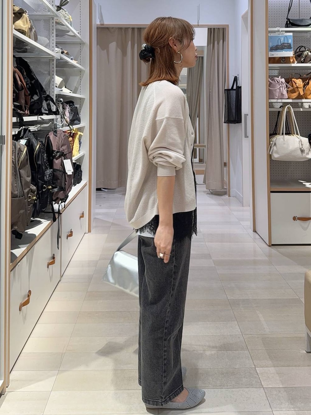 シルバー系のショルダーバッグ、ブラック系のデニムパンツ、ホワイト系のカーディガン/ボレロを着用したレディースの夏コーディネートの4枚目の写真