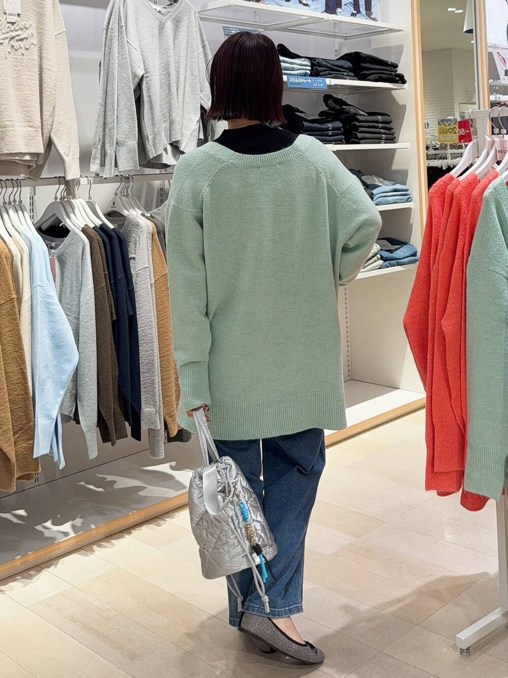 グレー系のバレエシューズ、シルバー系のハンドバッグ、ブルー系のデニムパンツを着用したレディースの秋コーディネートの5枚目の写真