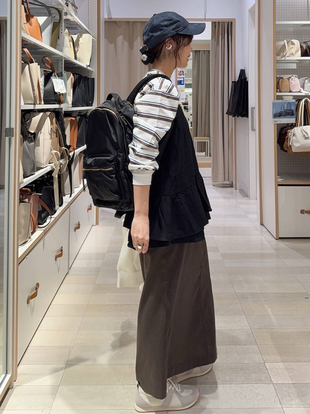 グレー系のスニーカー、ブラック系のバックパック/リュック、ホワイト系のパーカーを着用したレディースの春コーディネートの6枚目の写真