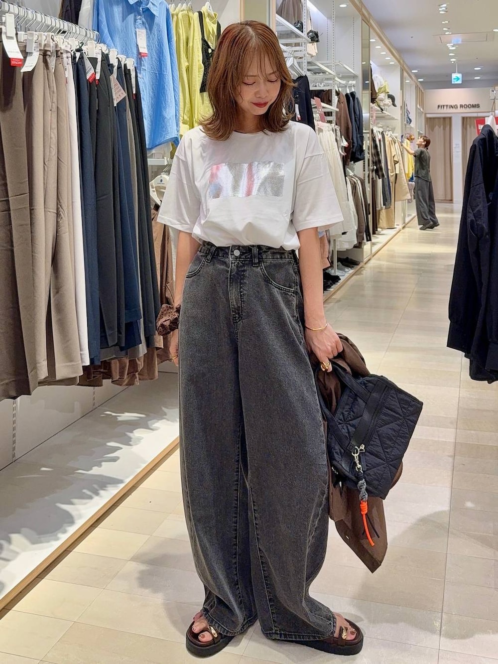 ブラック系のボストンバッグ、ブラック系のデニムパンツ、ホワイト系のTシャツ/カットソーを着用したレディースの夏コーディネートの2枚目の写真