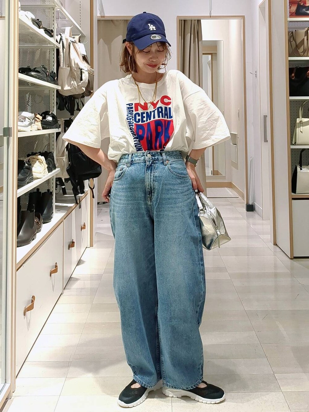 ブラック系のスニーカー、シルバー系のショルダーバッグ、ブルー系のデニムパンツを着用したレディースの春コーディネートの2枚目の写真