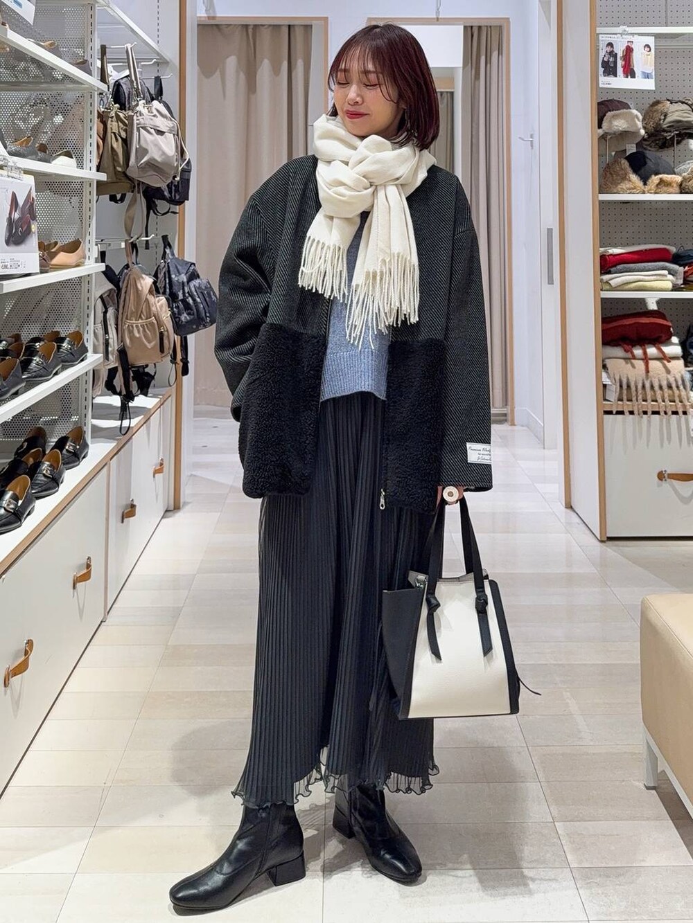 ホワイト系のショルダーバッグ、グレー系のノーカラージャケット、ブラック系のブーツを着用したレディースの秋コーディネートの3枚目の写真