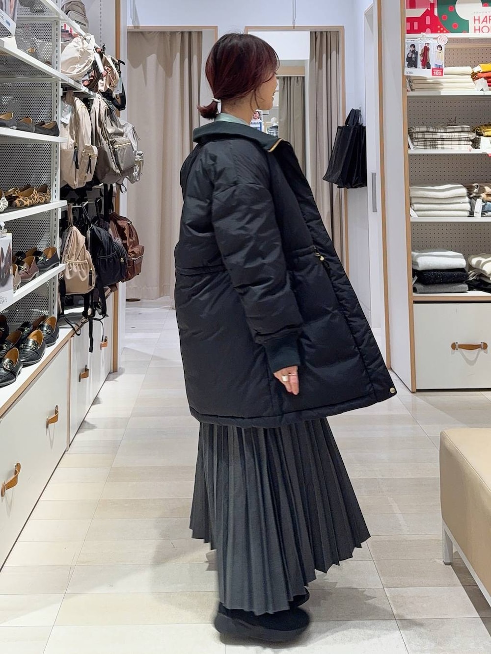 ホワイト系のショルダーバッグ、ブラック系のダウンジャケット/コート、ブラック系のブーツを着用したレディースの冬コーディネートの4枚目の写真