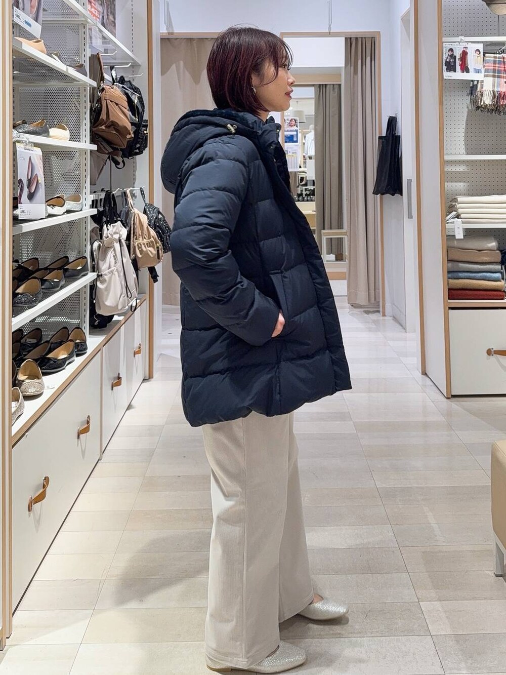 ブラック系のショルダーバッグ、シルバー系のパンプス、ブルー系のダウンジャケット/コートを着用したレディースの秋コーディネートの4枚目の写真