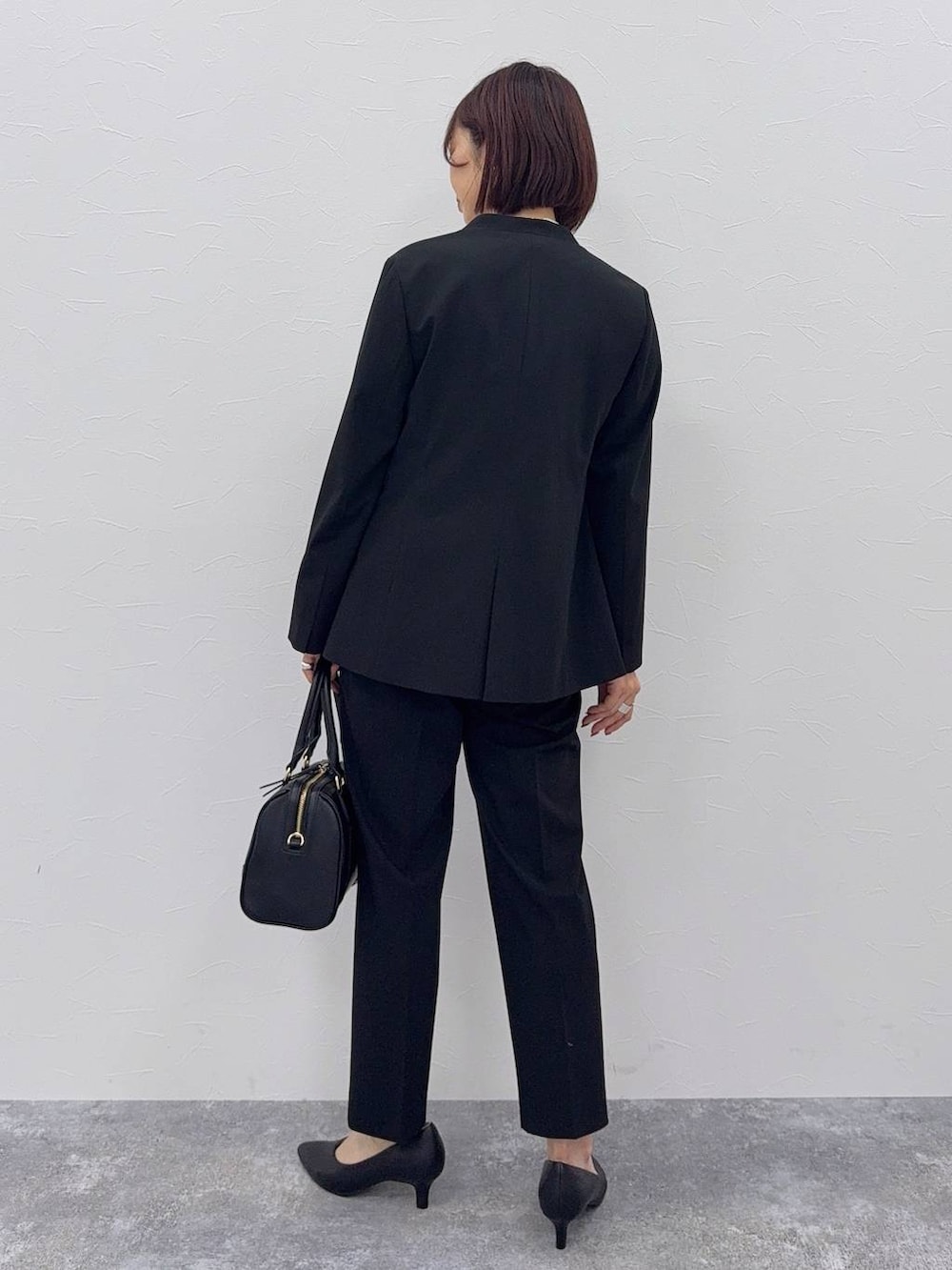 ブラック系のスラックス、ホワイト系のシャツ/ブラウス、ブラック系のボストンバッグを着用したレディースの秋コーディネートの3枚目の写真