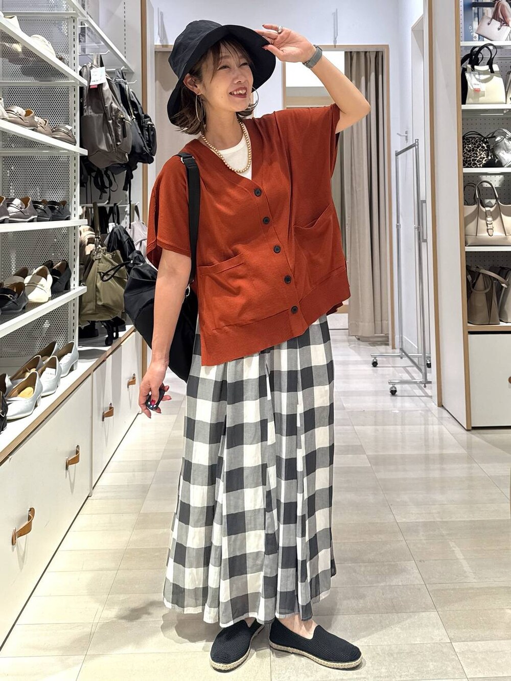 ホワイト系のスカート、ブラック系のスリッポン、オレンジ系のカーディガン/ボレロを着用したレディースの春コーディネートの2枚目の写真