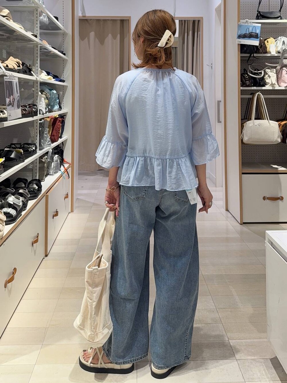 ホワイト系のトートバッグ、ブルー系のデニムパンツ、ホワイト系のサンダルを着用したレディースの春コーディネートの4枚目の写真
