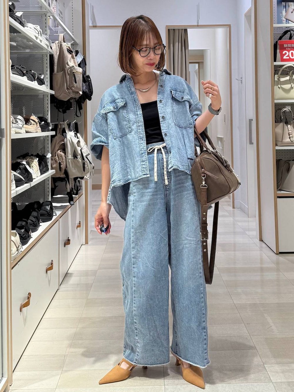 ベージュ系のパンプス、グリーン系のボストンバッグ、ブルー系のデニムパンツを着用したレディースの春コーディネートの2枚目の写真