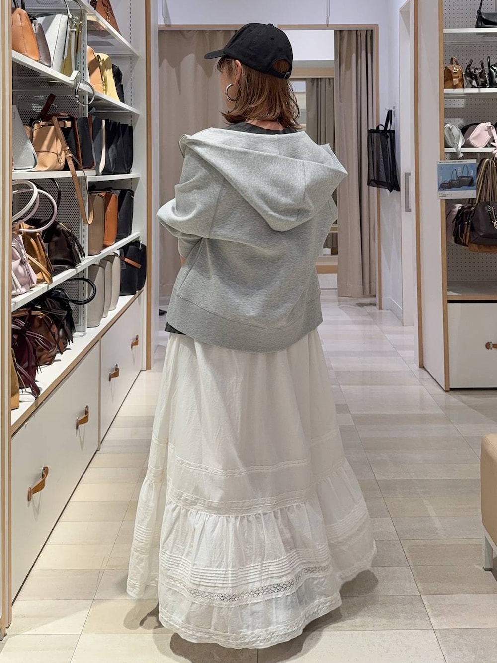 ブラック系のボストンバッグ、グレー系のパーカー、ホワイト系のスカートを着用したレディースの春コーディネートの6枚目の写真