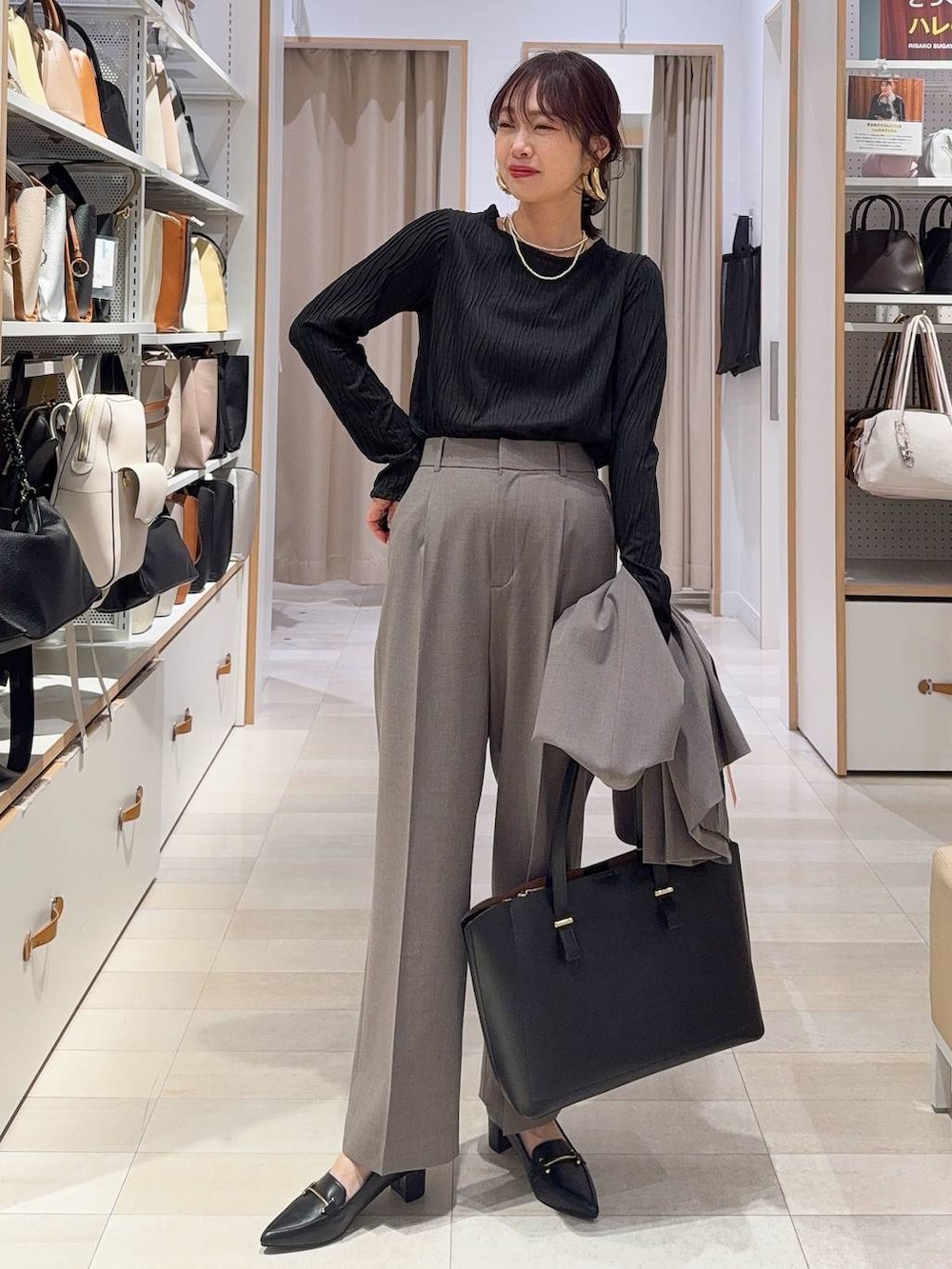 ブラウン系のスラックス、ブラック系のTシャツ/カットソー、ブラック系のトートバッグを着用したレディースの冬コーディネートの2枚目の写真