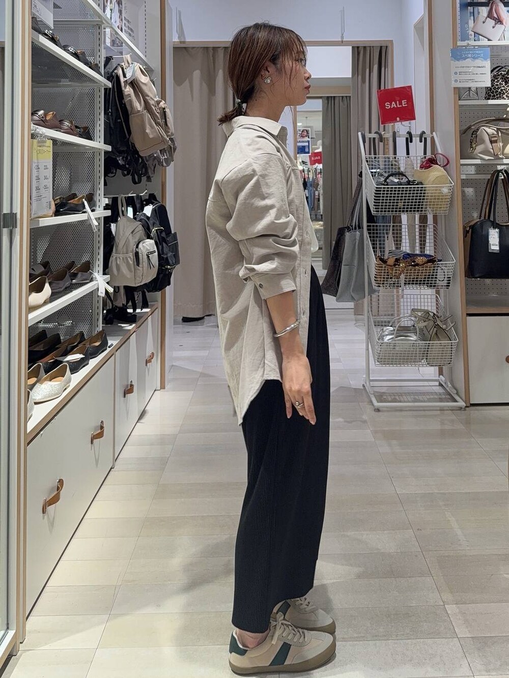 ベージュ系のスニーカー、ホワイト系のTシャツ/カットソー、ブラック系のショルダーバッグを着用したレディースの夏コーディネートの3枚目の写真