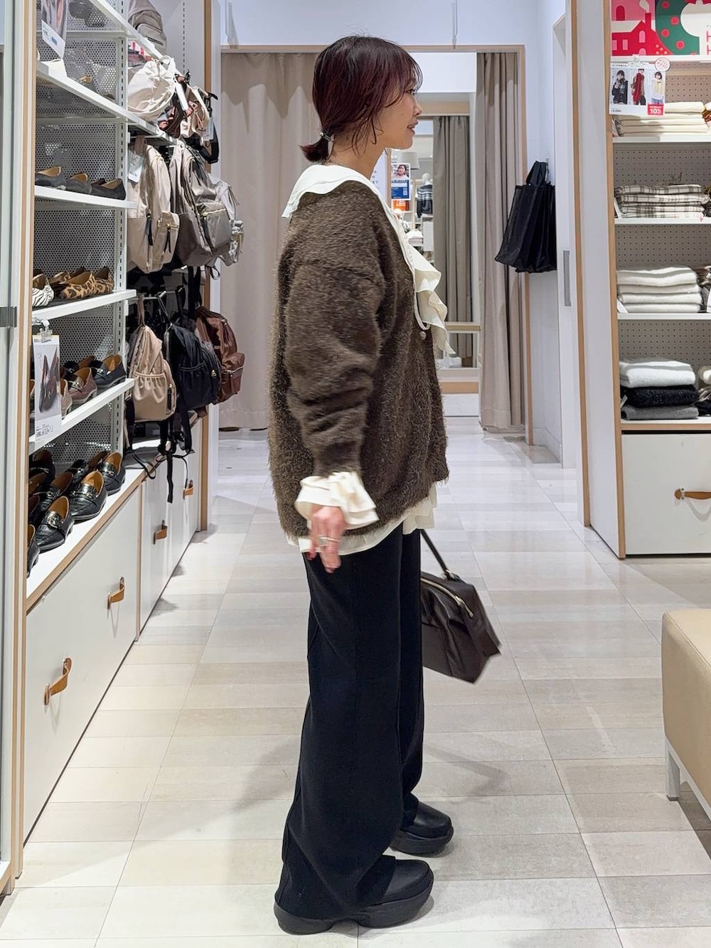 ブラウン系のボストンバッグ、ブラック系のブーツ、ブラウン系のカーディガン/ボレロを着用したレディースの冬コーディネートの5枚目の写真