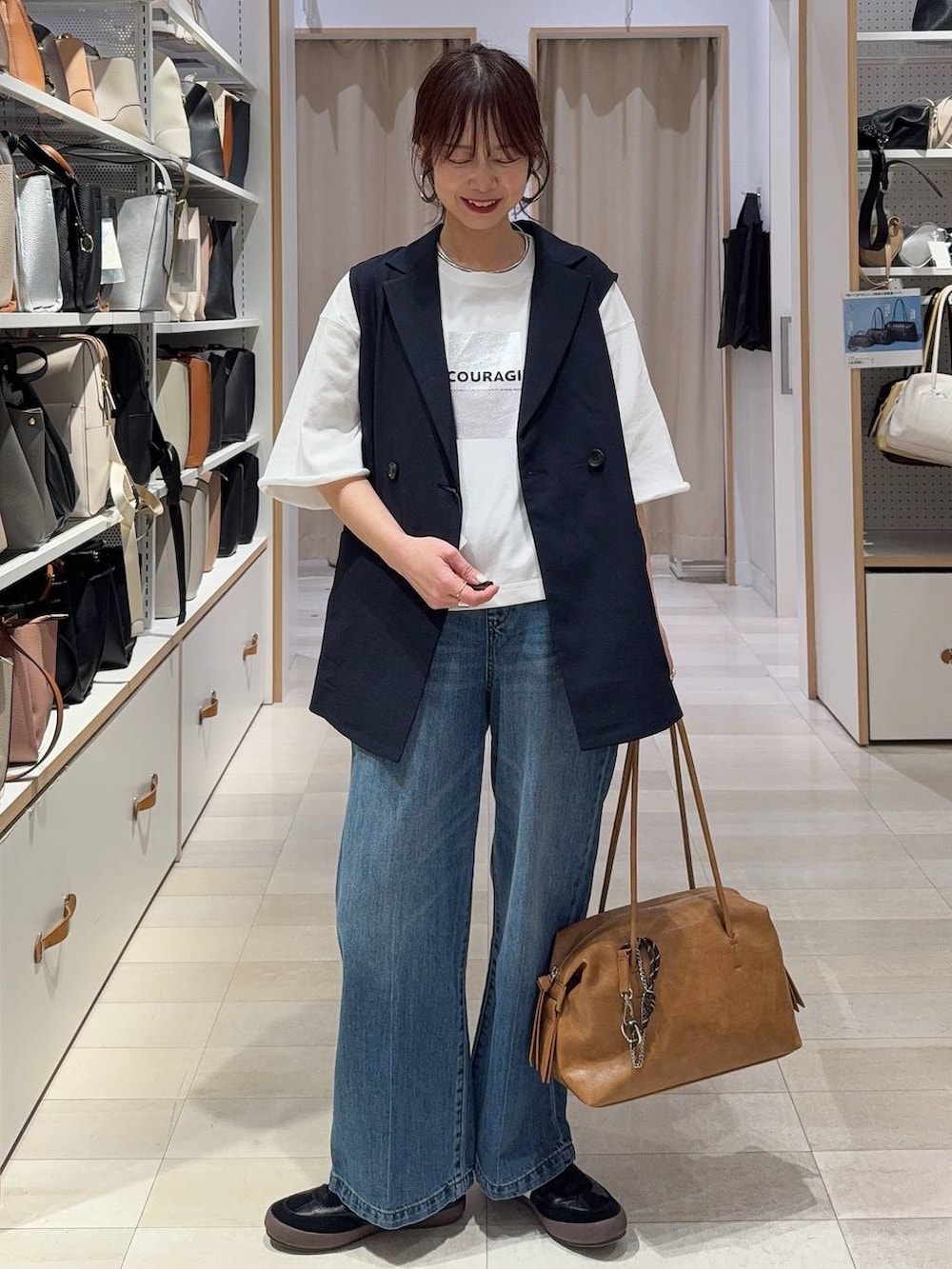 ブラック系のその他シューズ、ブラック系のボストンバッグ、ブルー系のベストを着用したレディースの春コーディネートの3枚目の写真