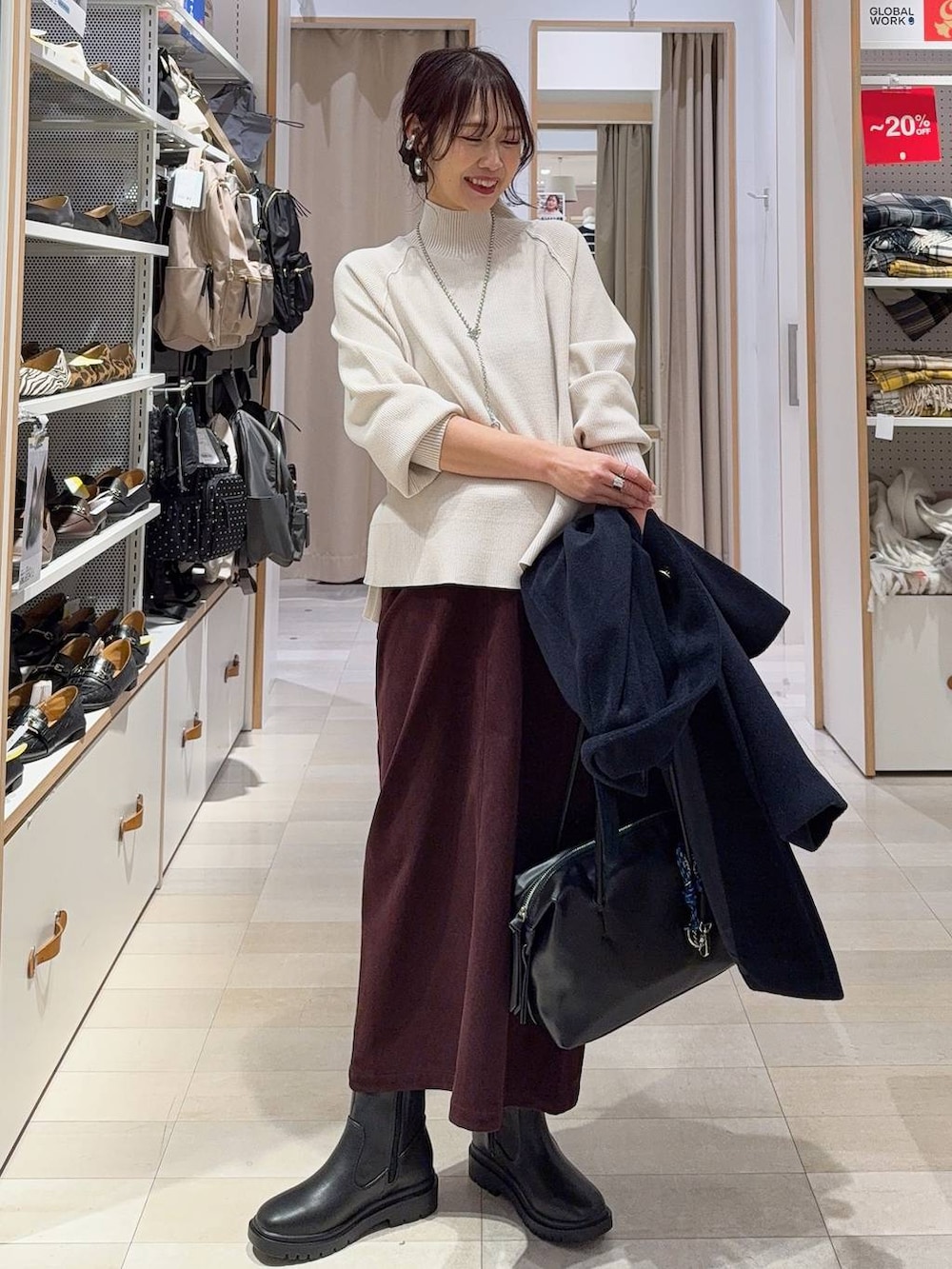 ブラック系のボストンバッグ、ブルー系のチェスターコート、レッド系のスカートを着用したレディースの冬コーディネートの3枚目の写真