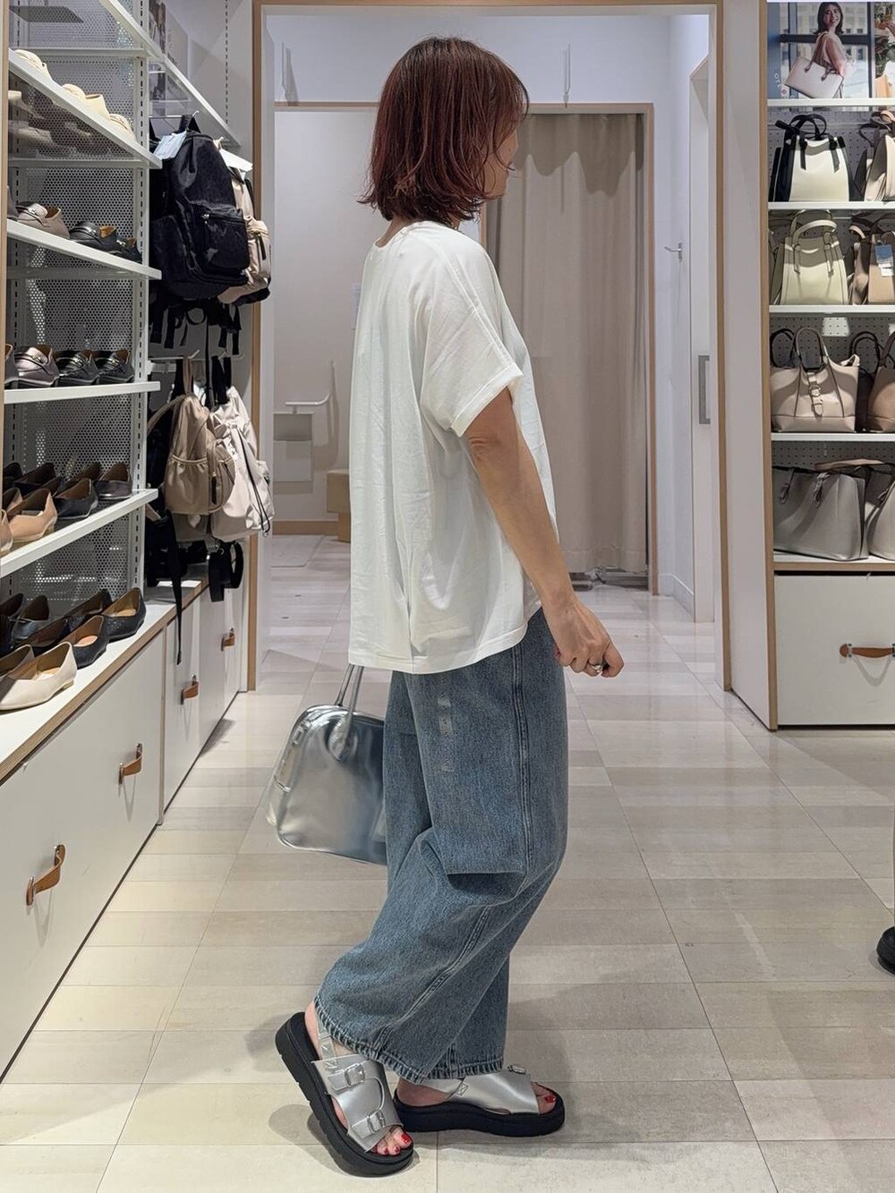 ブルー系のデニムパンツ、グレー系のボストンバッグ、シルバー系のサンダルを着用したレディースの夏コーディネートの3枚目の写真