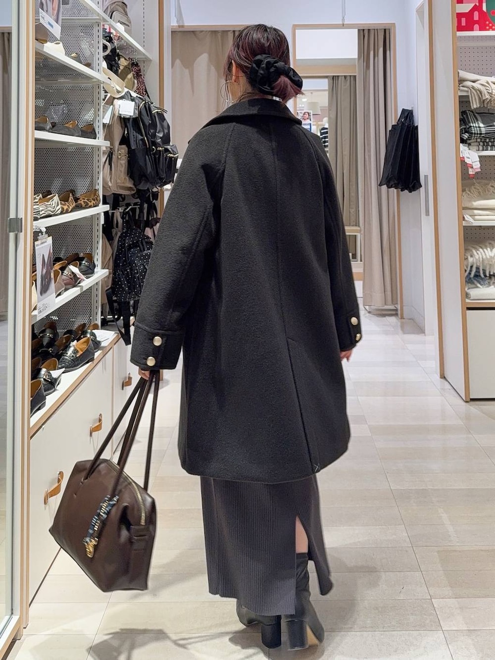 ブラウン系のボストンバッグ、ブラック系のチェスターコート、ホワイト系のTシャツ/カットソーを着用したレディースの冬コーディネートの7枚目の写真