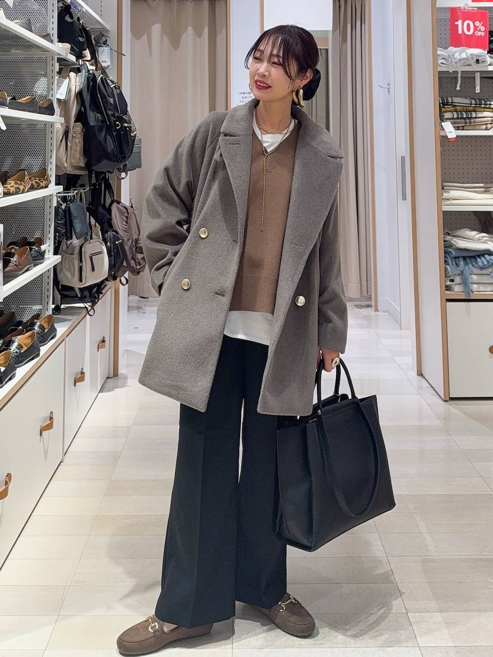 ブラウン系のチェスターコート、ブラック系のその他パンツ、ホワイト系のTシャツ/カットソーを着用したレディースの冬コーディネートの2枚目の写真