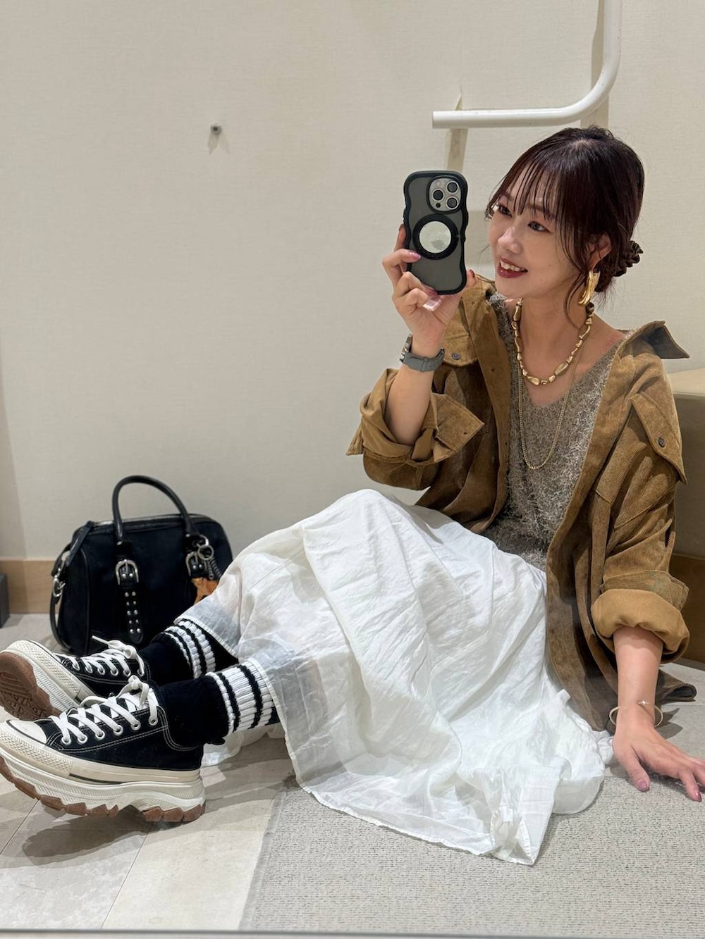 イエロー系のシャツ/ブラウス、ベージュ系のスカート、ブラック系のボストンバッグを着用したレディースの秋コーディネートの9枚目の写真