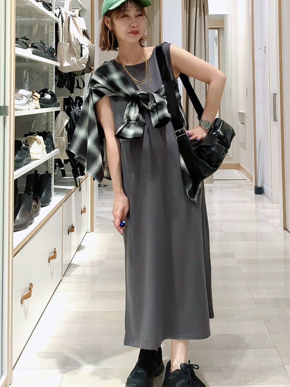 ブラック系のスニーカー、ブルー系のデニムパンツ、ベージュ系のワンピースを着用したレディースの春コーディネートの4枚目の写真