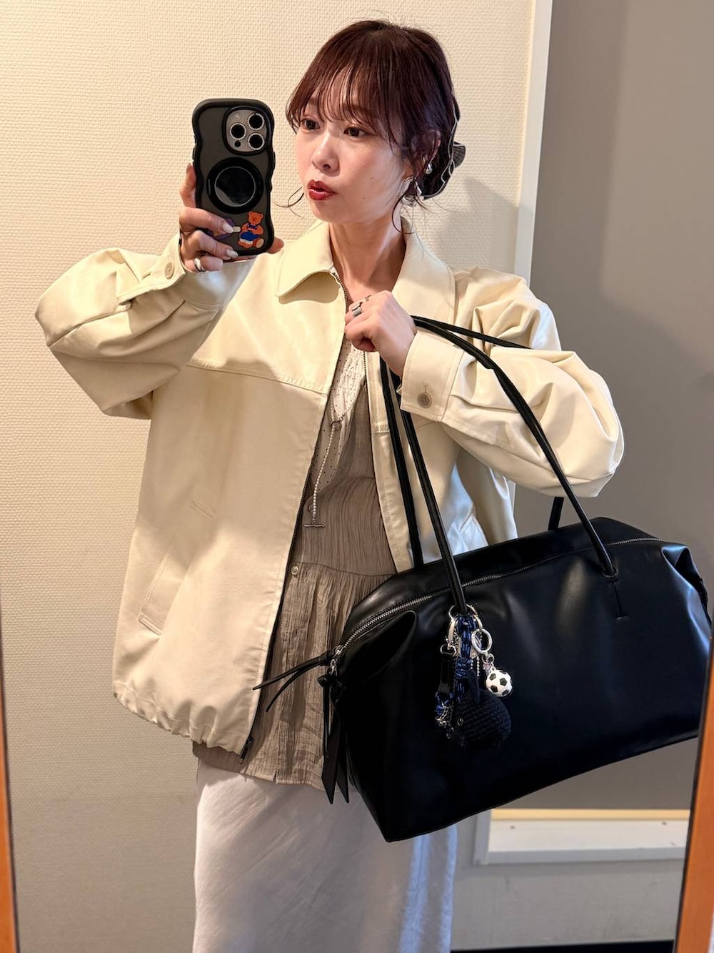 ホワイト系のブルゾン、ブラック系のショルダーバッグ、グレー系のスカートを着用したレディースの春コーディネートの2枚目の写真