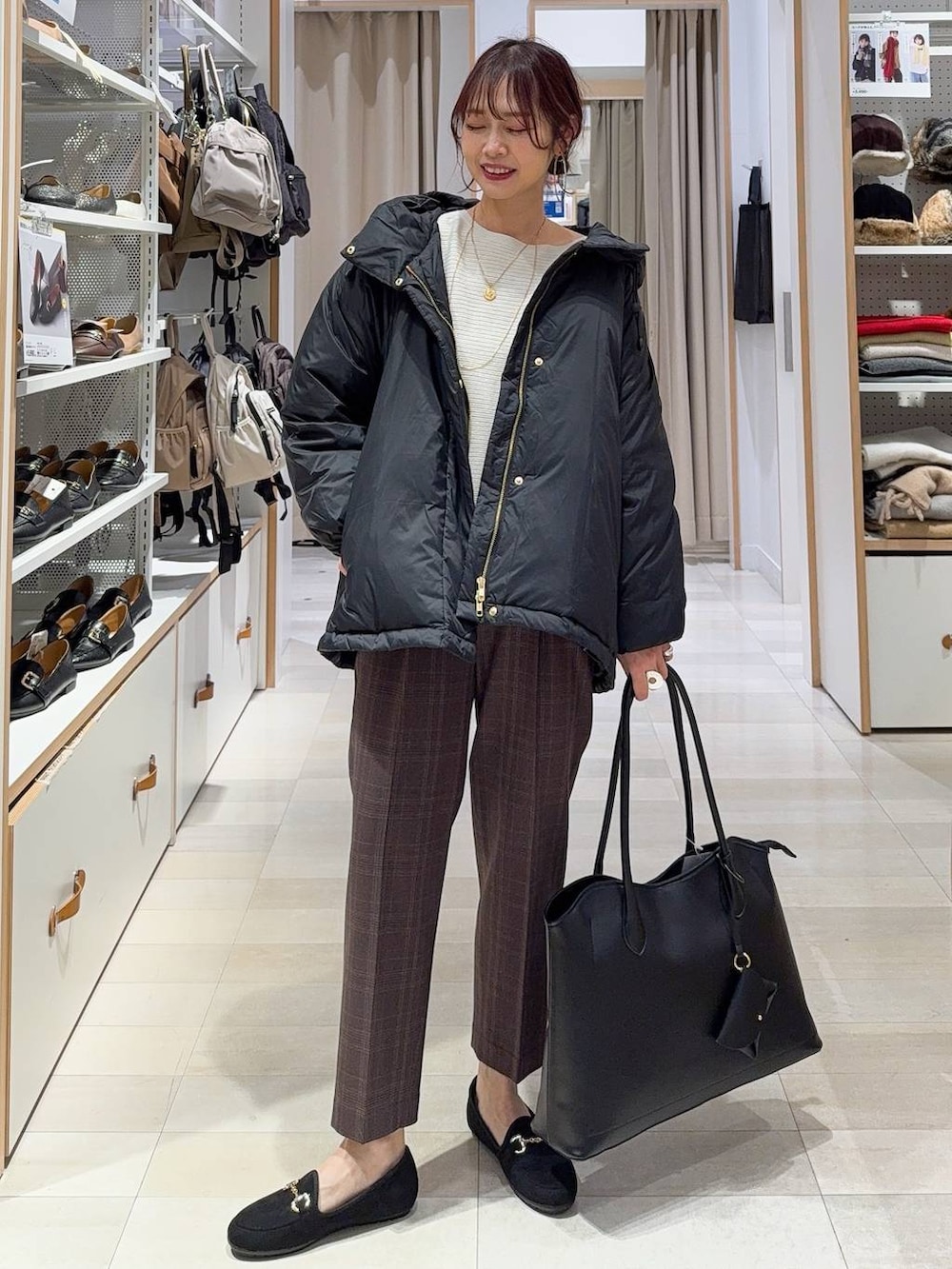 ブラック系のダウンジャケット/コート、ブラック系のトートバッグ、ブラウン系のその他パンツを着用したレディースの秋コーディネートの2枚目の写真