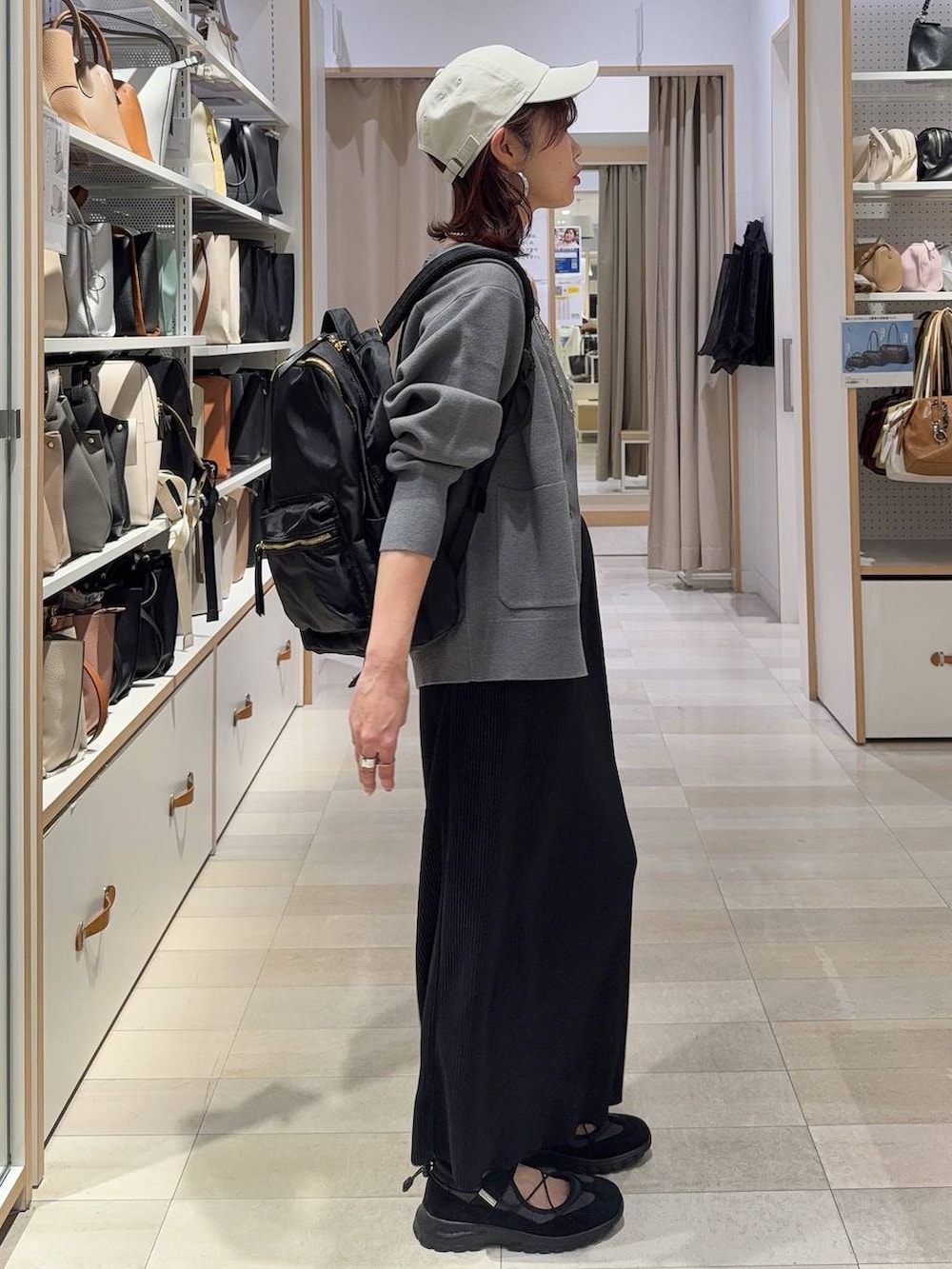 ブラック系のバックパック/リュック、グレー系のカーディガン/ボレロ、ブラウン系のタンクトップを着用したレディースの春コーディネートの2枚目の写真