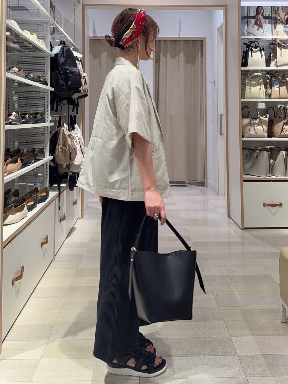 ブラック系のショルダーバッグ、ブラック系のスカート、ブラック系のサンダルを着用したレディースの夏コーディネートの5枚目の写真